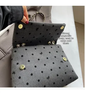 Detail of grey herringbone fabric bag showing strong magnetic closure and embroidery