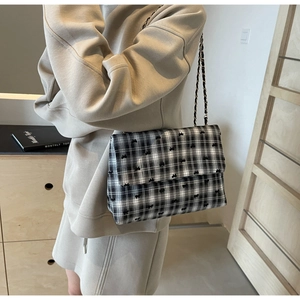 Détail du sac à bandoulière à carreaux avec nœuds et bandoulière chaîne dorée porté