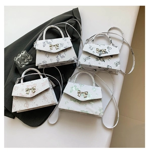 Detail view of four mini white crossbody bags featuring various butterfly and floral prints