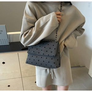 Detail of grey denim tote bag with black polka dots and embroidered bow decorations