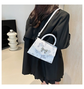Détail du sac bandoulière blanc en cuir PU avec motif papillon bleu et fermoir nœud argent