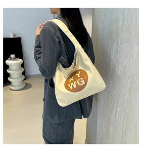 Close-up of canvas tote bag with a circular leather patch and embossed X.Y WG logo