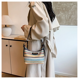 Detail of colorful rainbow striped straw bag with black leather strap and logo
