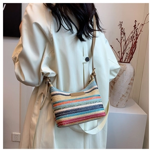Macro shot of colorful woven stripe texture and brand leather patch on a crossbody bucket bag