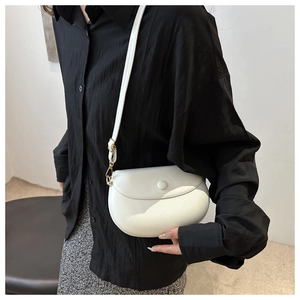 Detailed view of the white saddle bag featuring smooth faux leather and gold metal hardware
