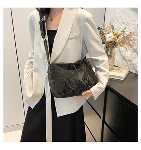 Detail of black crossbody tote with pleated texture and adjustable silver buckle