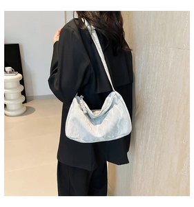 Close-up of silver pleated dumpling bag showing wavy texture and thick shoulder strap