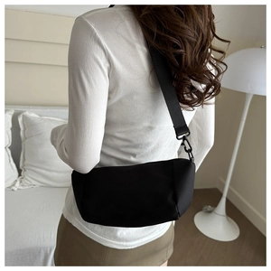 Rear view of a model wearing the black crescent crossbody bag made of matte nylon