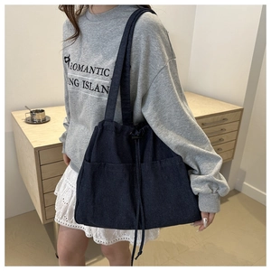 Detail of blue denim tote bag with functional drawstring pockets for commute