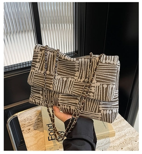 Detail of tweed texture and metal chain strap on the brown and white shoulder bag