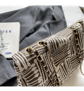 Detail of woven geometric pattern handbag featuring gold chain strap and metal eyelets