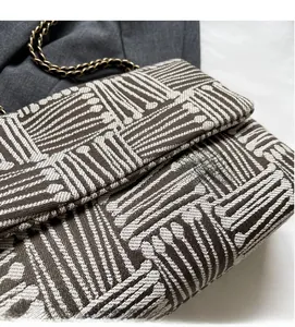 Close-up of geometric jacquard fabric and gold chain on the brown and white tote bag