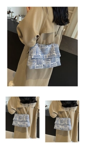 Detail of blue woven shoulder bag with geometric pattern and metal chain strap on model