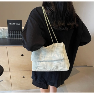 Detail of light green fabric shoulder bag with geometric patterns and gold chain strap