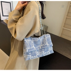 Close-up of blue and white woven fabric tote bag with elegant gold chain shoulder strap
