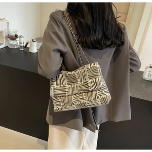Detail of woven brown and beige crossbody bag with premium gold chain strap and flap