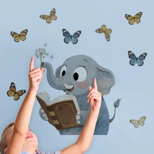 Bambino che interagisce con adesivi murali di elefante e farfalle nella cameretta