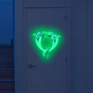 Glow-in-the-dark dolphin heart wall sticker illuminating a bedroom door in dark green light