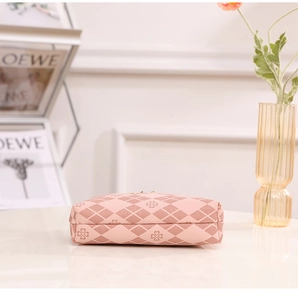 Pink quilted rhombic makeup bag with clover pattern on a white marble tabletop