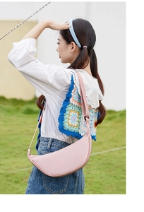Outdoor shot of a pink crescent nylon bag with an adjustable strap worn across the body