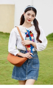 Outdoor close-up of an orange crescent crossbody bag with a wide adjustable shoulder strap