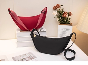 Detail of red and black crescent nylon crossbody bags in a minimalist home setting