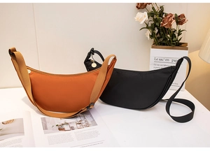 Nylon crescent crossbody bags in black and caramel colors on a minimalist desk setup