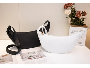 Detail of minimalist crescent shoulder bags in black and white with adjustable wide straps