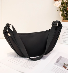 Detail of black nylon crescent bag with adjustable strap and golden metal ring