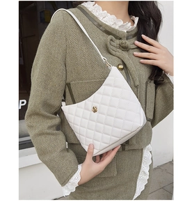 Dettaglio borsa trapuntata bianca con fibbia a fiore dorata su abito in tweed verde