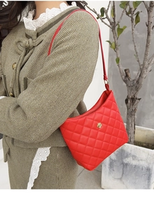 Dettaglio borsa a tracolla trapuntata rossa con chiusura floreale dorata e dettagli in metallo
