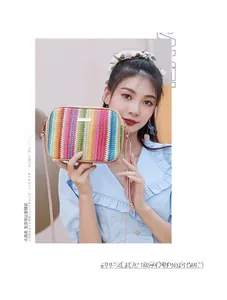 Detail of rainbow striped woven bag with metal plate and pink leather strap