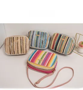 Detail view of colorful woven straw crossbody bags with zipper and leather straps