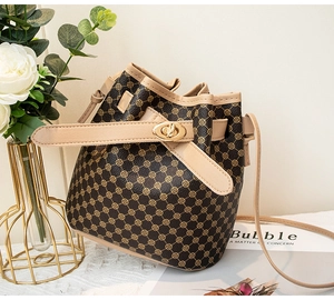 Gros plan d'un sac seau vintage avec motif monogramme et fermoir rotatif en métal