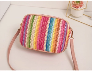 Detail view of rainbow striped woven straw bag with pink strap and metal hardware
