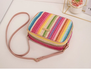 Side view of rainbow striped woven straw bag with pink strap and golden zipper detail