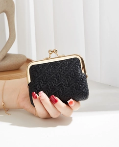 Close-up of black woven leather mini wallet with vintage metal clasp held by a model