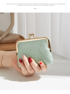 Close-up of mint green coin purse featuring herringbone texture and golden clasp