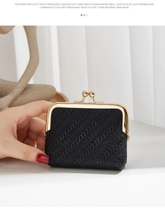 Detail of a mini shell coin purse with black woven texture and golden metal clasp closure