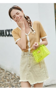 Close-up of neon green transparent jelly bag with golden chain and metal turn lock