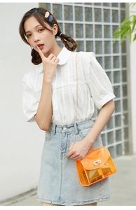 Clear orange jelly crossbody bag with metal chain strap shown on a female model