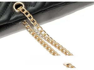 Detailed macro view of the gold chain hardware connection on black quilted tote bag