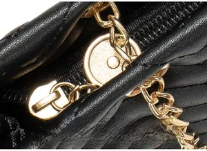 Detailed close-up of golden hardware zipper and magnetic snap on black quilted tote bag