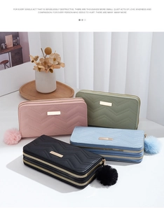 Detailed view of quilted long wallets with wave patterns and faux fur pompom charms