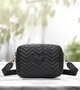 Detail of wave quilted stitching and heart embroidery on black crossbody camera bag