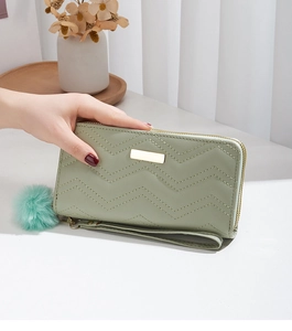 Close-up of mint green long wallet with V-quilt pattern and fluffy pompom charm