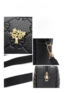 Detail of black pebbled leather crossbody bag with tree charm and gold-tone hardware