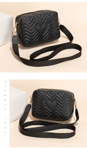 Detail view of heart-quilted crossbody camera bag with gold hardware and black fabric strap