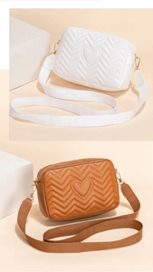 Detail of V-quilted and heart-embroidered camera bag with canvas strap and gold hardware