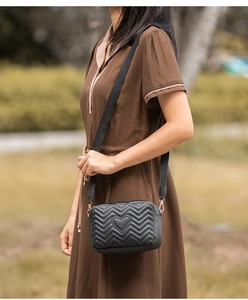 Detail of black crossbody camera bag with heart embroidery and V-quilted texture